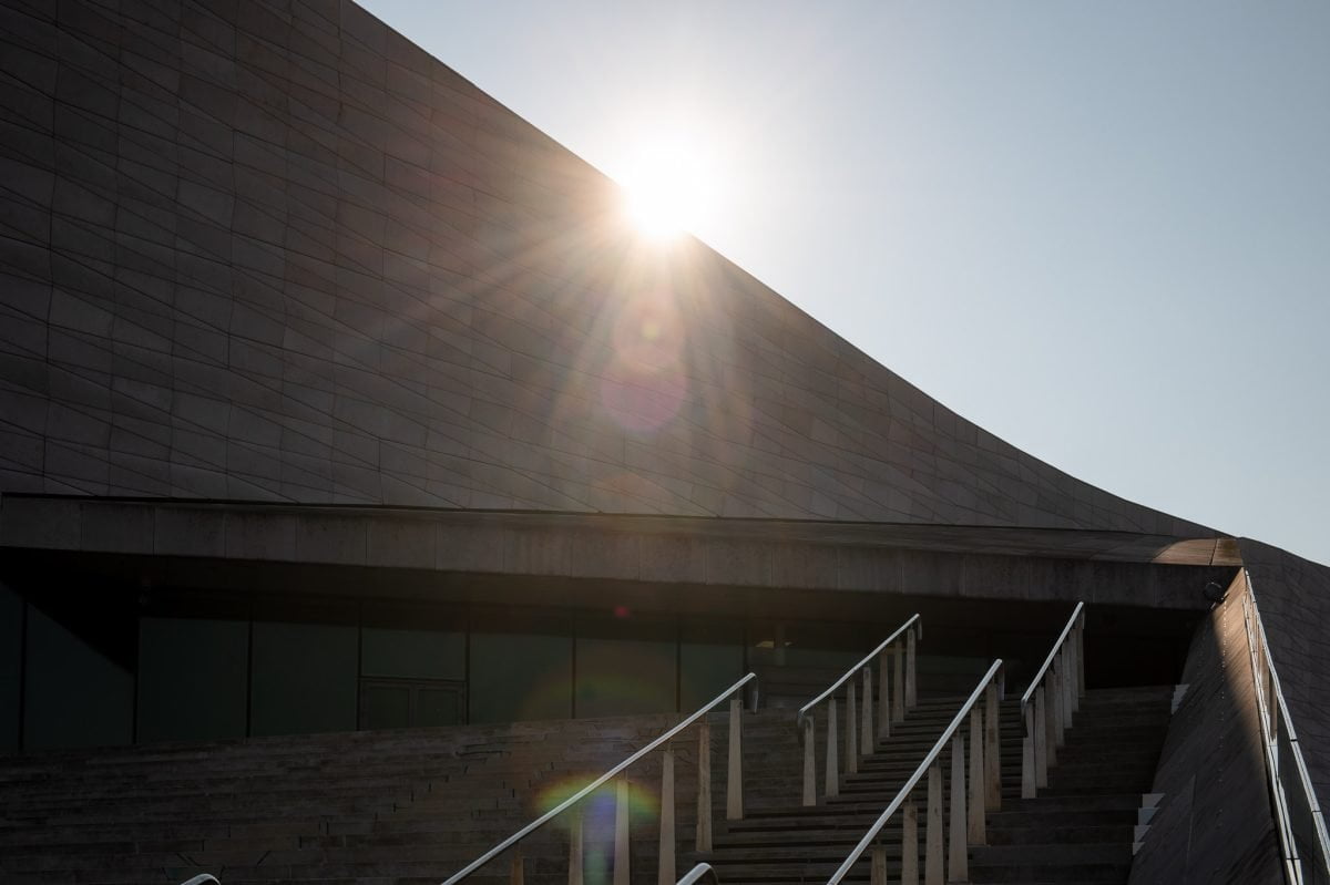 Standing on the steps of the Museum of Liverpool facing into the sun. The handles on the steps are backlit by the sun.