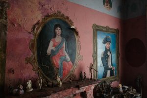 Paintings, including the frames, are painted onto the walls in a pink walled room. One is an admiral of the sea. Another is an Indian woman.