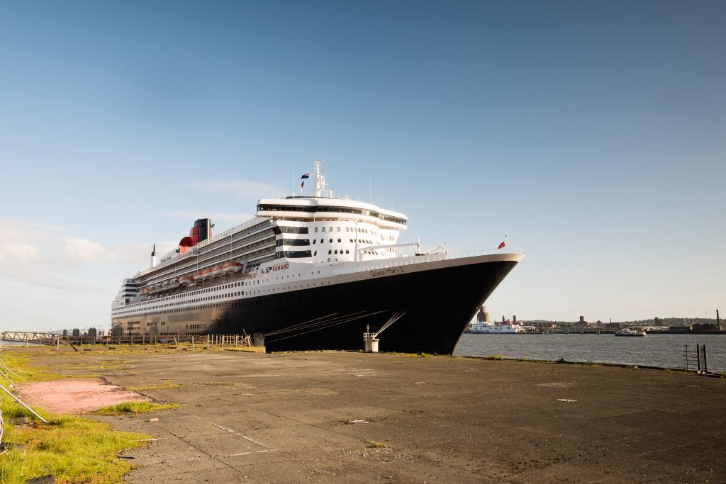 The Cunard ship Queen Mary 2 docked in Liverpool on a sunny day.
