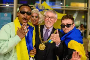 Ukrainian Eurovision winners Tvorchi pose for a photo with the Mayor of Liverpool while drag queen Filla Crack sneaks in behind.