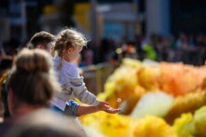A father holds up his young girl as she catches a single bit of foam.