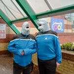 Two people dressed in Star Trek uniforms and dolphin masks stand outside a swimming pool.