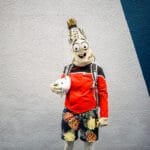 A person in a corn cob costume and glasses holds a plushie at Sci-Fi Weekender.