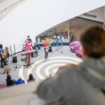 A band performs live music in the atrium of the Museum of Liverpool.  Spectators are seated around the performance area, watching.