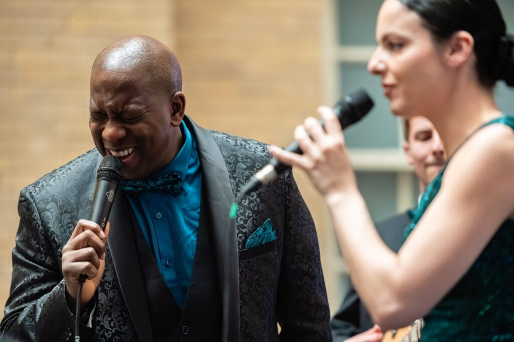 A man and a woman singing into microphones at an event.