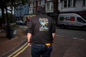 A person wearing a hoodie with the words 'AuDHD It's Not a Disability It's a Different Ability' at Wirral Pride 2025 in New Brighton.